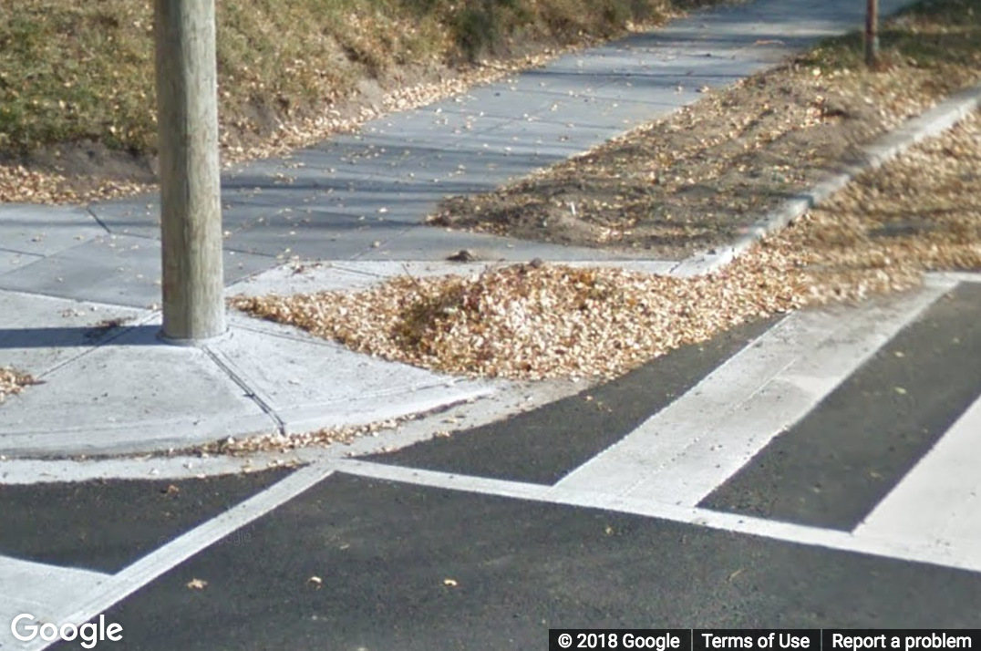 A Street View image of a curb ramp with heavy debris