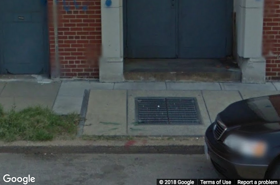 A Street View image of a grate on a sidewalk